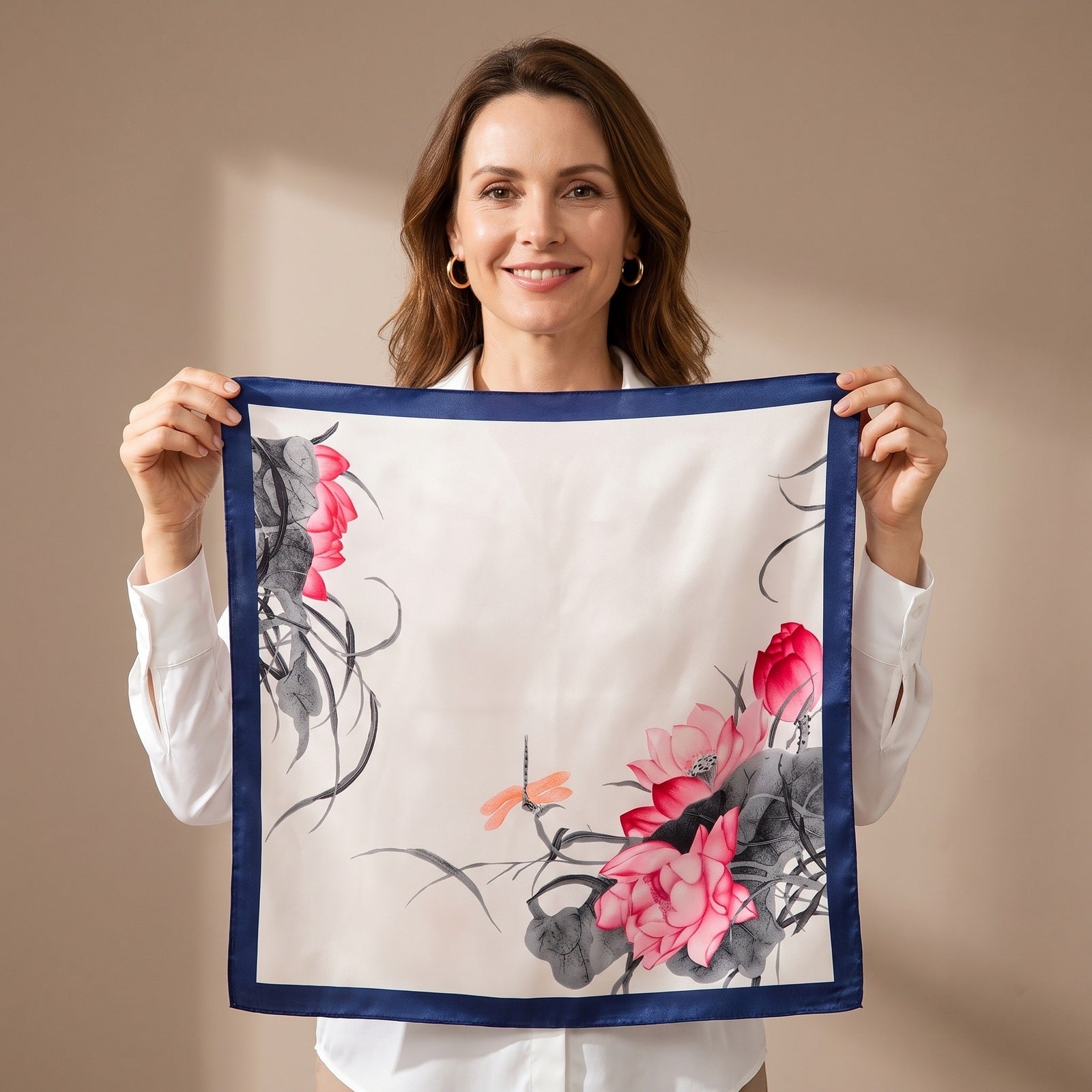 A woman holding the Lotus & Dragonfly Silk Square Scarf 90x90cm open so the whole print is visible