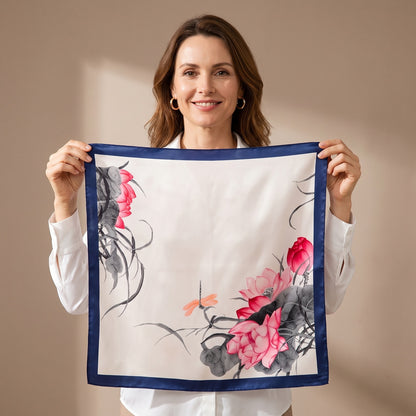A woman holding the Lotus & Dragonfly Silk Square Scarf 90x90cm open so the whole print is visible